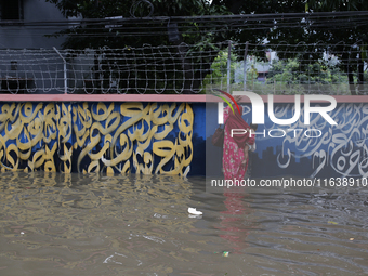 A woman walks through a waterlogged street after heavy rainfall in Dhaka, Bangladesh, on October 5, 2024. The flash flood hits several areas...