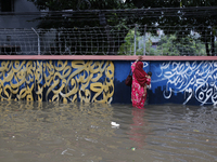 A woman walks through a waterlogged street after heavy rainfall in Dhaka, Bangladesh, on October 5, 2024. The flash flood hits several areas...