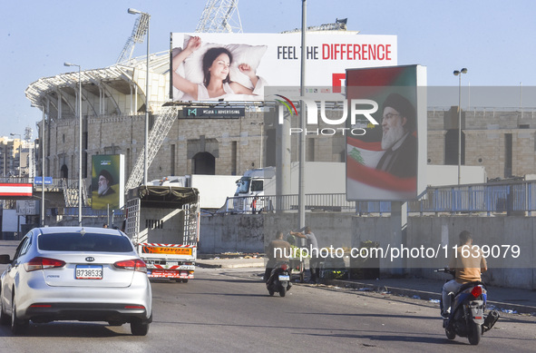 Workers hang billboards bearing a portrait of slain Lebanese Hezbollah Leader Hassan Nasrallah along the airport highway in Beirut, Lebanon,...