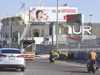 Workers hang billboards bearing a portrait of slain Lebanese Hezbollah Leader Hassan Nasrallah along the airport highway in Beirut, Lebanon,...