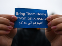 KRAKOW, POLAND - OCTOBER 5:
A pro-Israeli supporter holds a sign reading 'Bring Them Home' as pro-Palestinian activists rally in Krakow's UN...