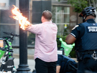 Police help a man who tried to set himself on fire as people demonstrate to mark one year of the war between Hamas and Israel in front of th...