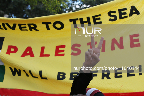 A woman makes the victory sign during a demonstration in solidarity with Palestinian people at The Grassy Knoll to mark the first anniversar...