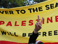 A woman makes the victory sign during a demonstration in solidarity with Palestinian people at The Grassy Knoll to mark the first anniversar...