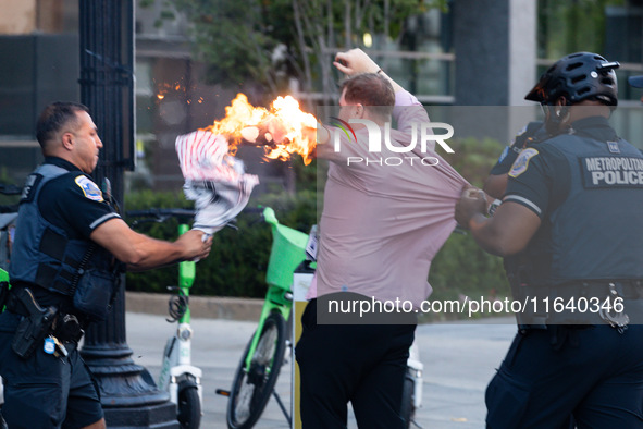 Police help a man who tried to set himself on fire as people demonstrate to mark one year of the war between Hamas and Israel in front of th...