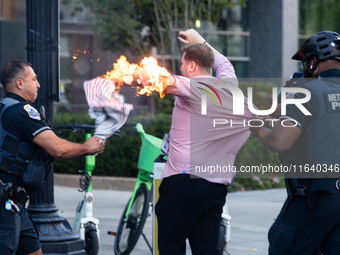 Police help a man who tried to set himself on fire as people demonstrate to mark one year of the war between Hamas and Israel in front of th...