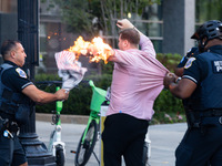 Police help a man who tried to set himself on fire as people demonstrate to mark one year of the war between Hamas and Israel in front of th...