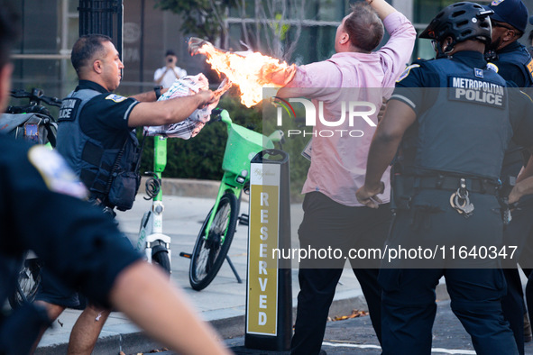 Police help a man who tried to set himself on fire as people demonstrate to mark one year of the war between Hamas and Israel in front of th...