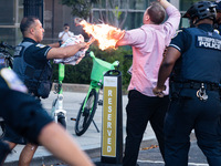 Police help a man who tried to set himself on fire as people demonstrate to mark one year of the war between Hamas and Israel in front of th...