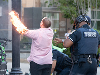 Police help a man who tried to set himself on fire as people demonstrate to mark one year of the war between Hamas and Israel in front of th...