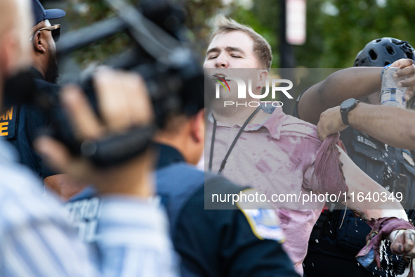 Police help a man who tried to set himself on fire as people demonstrate to mark one year of the war between Hamas and Israel in front of th...