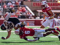 Wisconsin Badgers cornerback Xavier Lucas #6 sends Purdue running back Devin Mockobee #45 airborne at Camp Randall Stadium in Madison, Wisco...