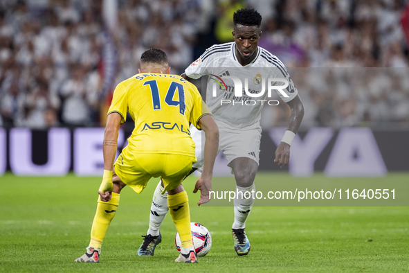 Vinicius Junior of Real Madrid CF (right) is in action with the ball against Santi Comesana of Villarreal CF (left) during the La Liga EA Sp...