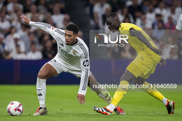 Jude Bellingham of Real Madrid CF (L) is in action with the ball against Pape Gueye of Villarreal CF (R) during the La Liga EA Sports 2024/2...