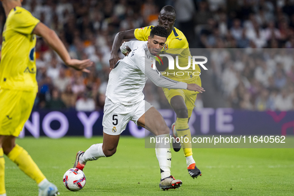 Jude Bellingham of Real Madrid CF (L) is in action with the ball against Pape Gueye of Villarreal CF (R) during the La Liga EA Sports 2024/2...