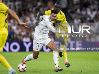 Jude Bellingham of Real Madrid CF (L) is in action with the ball against Pape Gueye of Villarreal CF (R) during the La Liga EA Sports 2024/2...