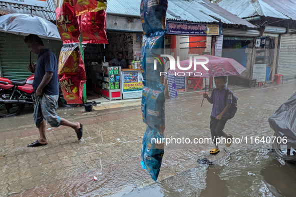 Children return from school during heavy rain in Feni, Bangladesh, on October 6, 2024. Climate change makes monsoons more extreme. Monsoons...