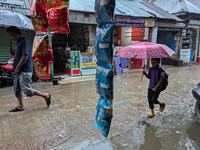 Children return from school during heavy rain in Feni, Bangladesh, on October 6, 2024. Climate change makes monsoons more extreme. Monsoons...