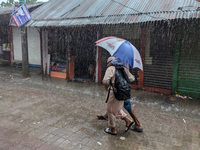 Children return from school during heavy rain in Feni, Bangladesh, on October 6, 2024. Climate change makes monsoons more extreme. Monsoons...