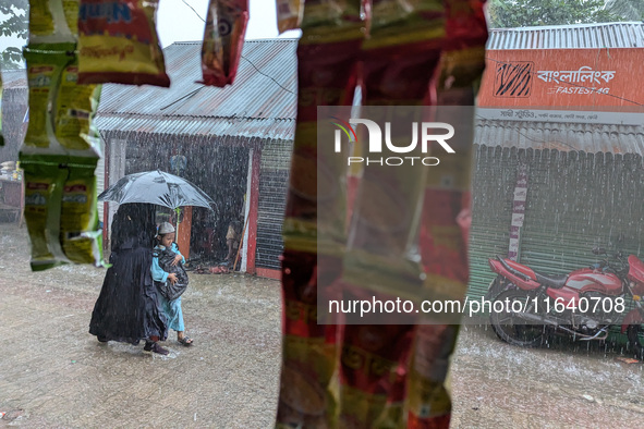 Children return from school during heavy rain in Feni, Bangladesh, on October 6, 2024. Climate change makes monsoons more extreme. Monsoons...