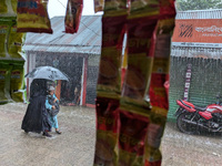 Children return from school during heavy rain in Feni, Bangladesh, on October 6, 2024. Climate change makes monsoons more extreme. Monsoons...