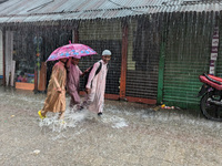 Children return from school during heavy rain in Feni, Bangladesh, on October 6, 2024. Climate change makes monsoons more extreme. Monsoons...