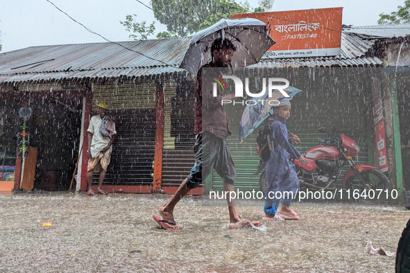 Children return from school during heavy rain in Feni, Bangladesh, on October 6, 2024. Climate change makes monsoons more extreme. Monsoons...