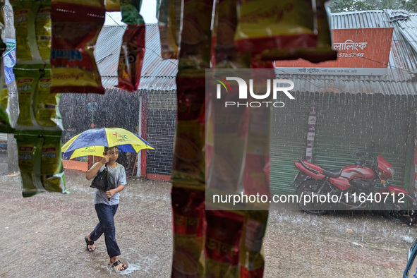 Children return from school during heavy rain in Feni, Bangladesh, on October 6, 2024. Climate change makes monsoons more extreme. Monsoons...