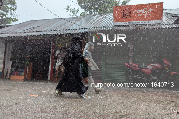 Children return from school during heavy rain in Feni, Bangladesh, on October 6, 2024. Climate change makes monsoons more extreme. Monsoons...