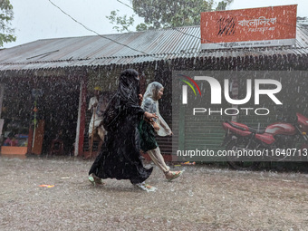 Children return from school during heavy rain in Feni, Bangladesh, on October 6, 2024. Climate change makes monsoons more extreme. Monsoons...