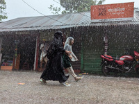 Children return from school during heavy rain in Feni, Bangladesh, on October 6, 2024. Climate change makes monsoons more extreme. Monsoons...