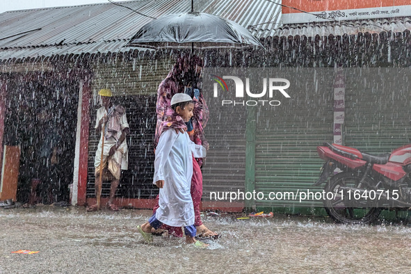 Children return from school during heavy rain in Feni, Bangladesh, on October 6, 2024. Climate change makes monsoons more extreme. Monsoons...