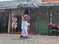 Children return from school during heavy rain in Feni, Bangladesh, on October 6, 2024. Climate change makes monsoons more extreme. Monsoons...