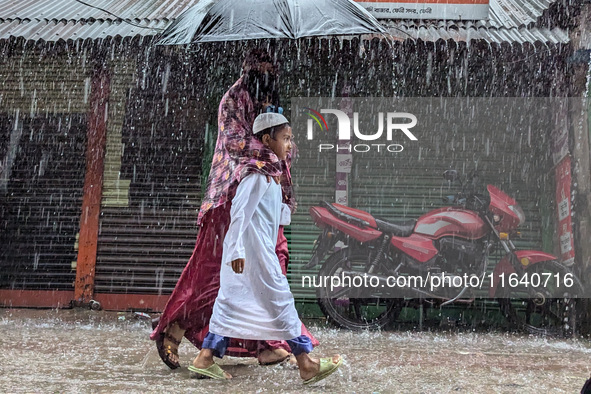 Children return from school during heavy rain in Feni, Bangladesh, on October 6, 2024. Climate change makes monsoons more extreme. Monsoons...