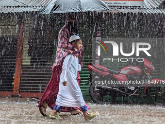 Children return from school during heavy rain in Feni, Bangladesh, on October 6, 2024. Climate change makes monsoons more extreme. Monsoons...