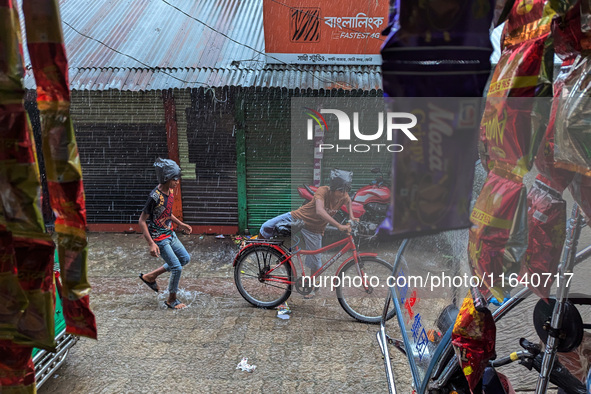 Children ride bicycles during heavy rain in Feni, Bangladesh, on October 6, 2024. Climate change makes monsoons more extreme. Monsoons becom...