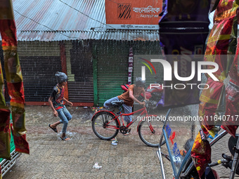 Children ride bicycles during heavy rain in Feni, Bangladesh, on October 6, 2024. Climate change makes monsoons more extreme. Monsoons becom...