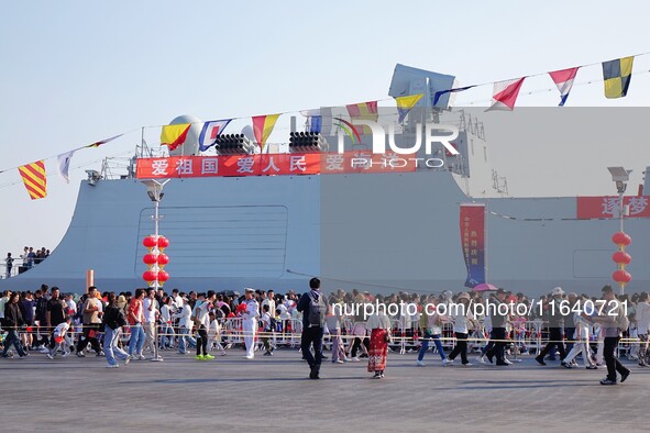 Tourists visit a warship at the port of the International Sailing Center in Qingdao, China, on October 3, 2024. 