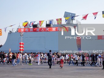 Tourists visit a warship at the port of the International Sailing Center in Qingdao, China, on October 3, 2024. (