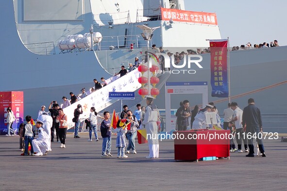 Tourists visit a warship at the port of the International Sailing Center in Qingdao, China, on October 3, 2024. 