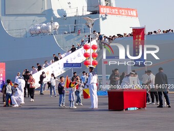 Tourists visit a warship at the port of the International Sailing Center in Qingdao, China, on October 3, 2024. (