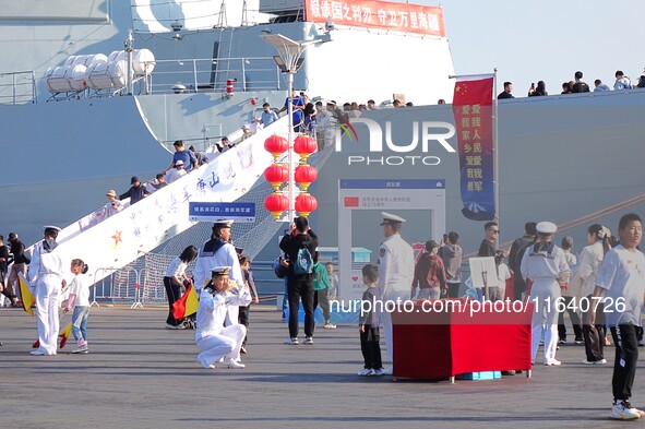 Tourists visit a warship at the port of the International Sailing Center in Qingdao, China, on October 3, 2024. 