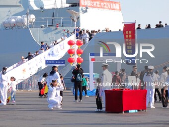 Tourists visit a warship at the port of the International Sailing Center in Qingdao, China, on October 3, 2024. (