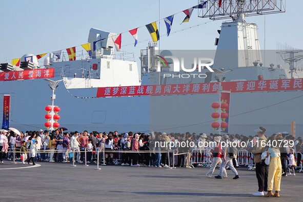 Tourists visit a warship at the port of the International Sailing Center in Qingdao, China, on October 3, 2024. 