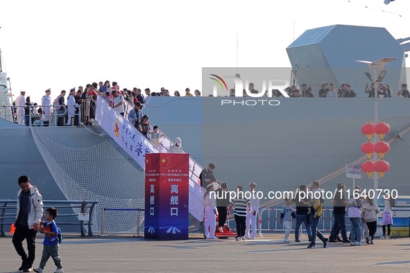 Tourists visit a warship at the port of the International Sailing Center in Qingdao, China, on October 3, 2024. 