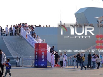 Tourists visit a warship at the port of the International Sailing Center in Qingdao, China, on October 3, 2024. (