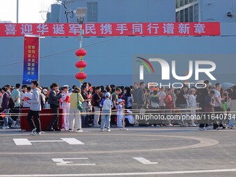 Tourists visit a warship at the port of the International Sailing Center in Qingdao, China, on October 3, 2024. (