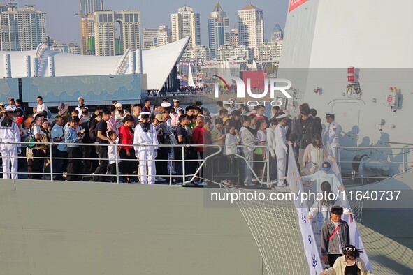 Tourists visit a warship at the port of the International Sailing Center in Qingdao, China, on October 3, 2024. 