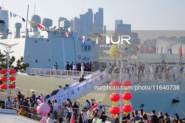 Tourists visit a warship at the port of the International Sailing Center in Qingdao, China, on October 3, 2024. 