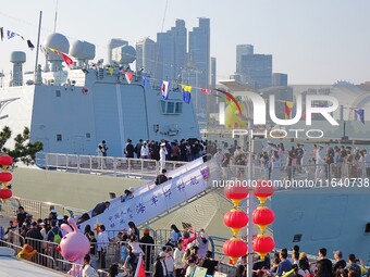 Tourists visit a warship at the port of the International Sailing Center in Qingdao, China, on October 3, 2024. (